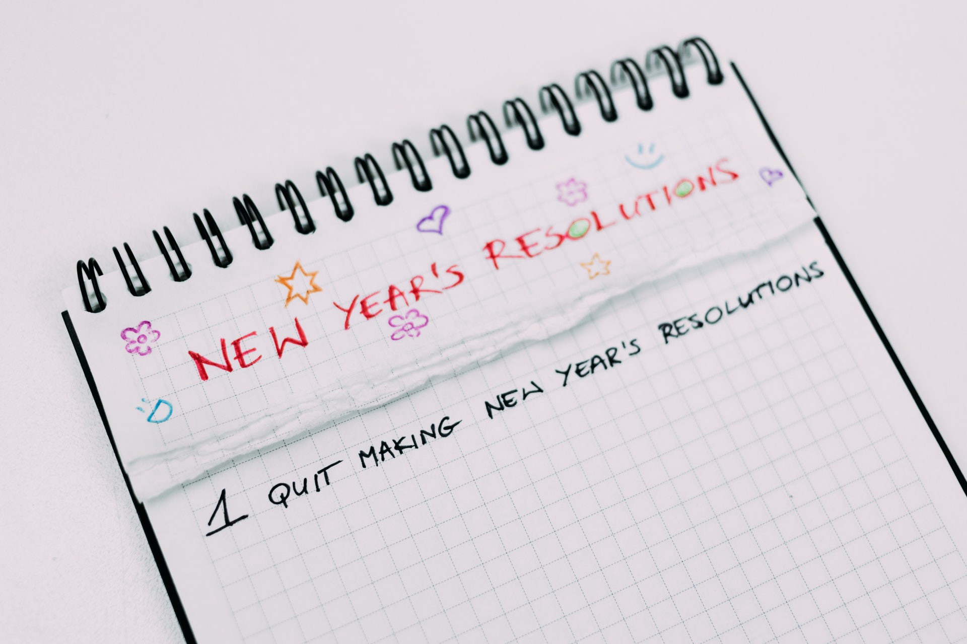 A notebook with New Year's Resolutions written on the top. #1 Quit Making New Year's Resolutions.